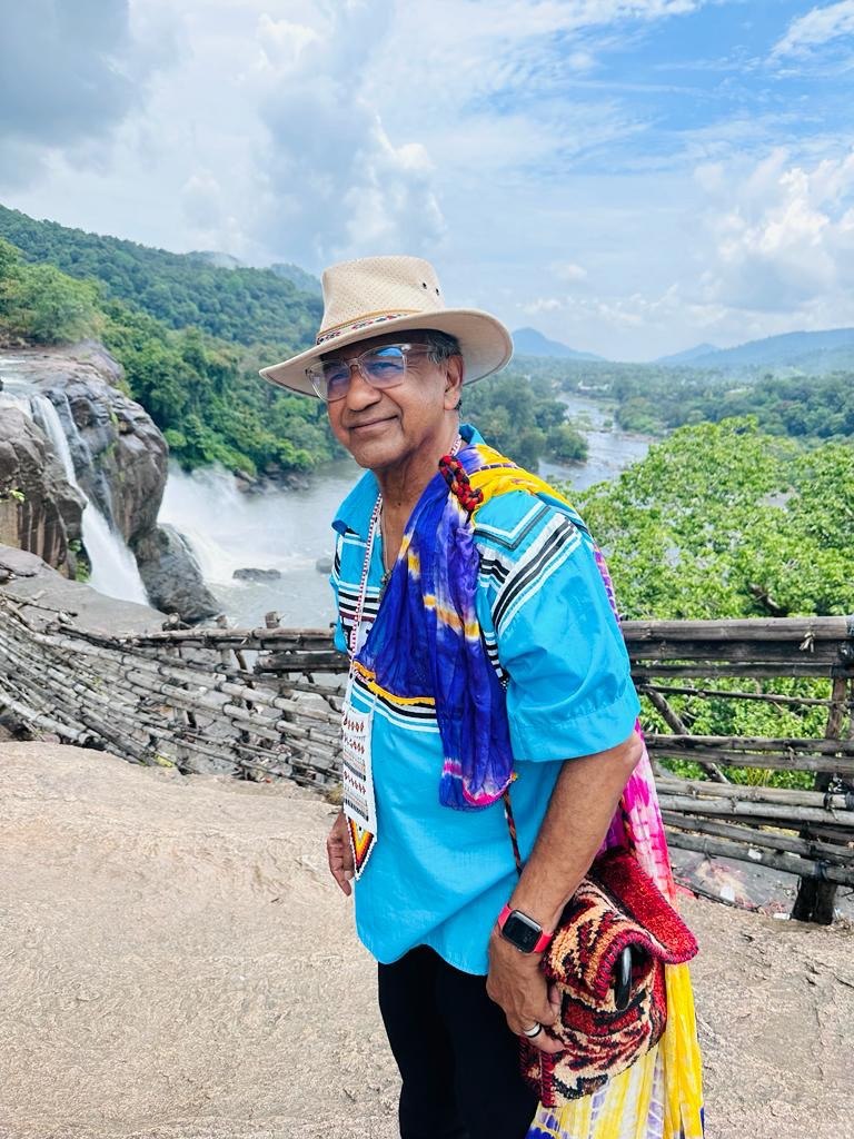 The Physician Anthropologist standing near a waterfall and mountain landscape